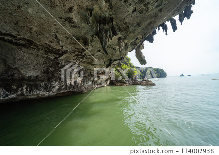 Natural stalactite and stalagmite rock stone cliff hang from cave ceiling in cave with lake river sea. Environmental explore. Landscape background. Erosion Natural stalactite and stalagmite rock stone cliff hang from cave ceiling in cave with lake river sea. Environmental explore. Landscape background. Erosion 114002938