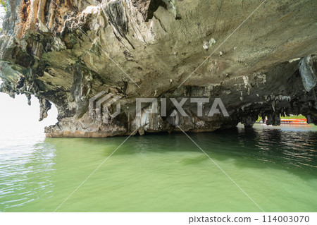 Natural stalactite and stalagmite rock stone cliff hang from cave ceiling in cave with lake river sea. Environmental explore. Landscape background. Erosion 114003070