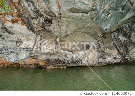 Natural stalactite and stalagmite rock stone cliff hang from cave ceiling in cave with lake river sea. Environmental explore. Landscape background. Erosion 114003072