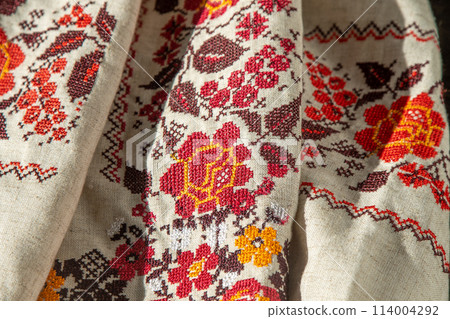 Ukrainian clothes embroidered shirt. Red orange and black threads background. Vyshyvanka is a symbol of Ukraine. Embroidery cross stitching. National Ukrainian stitch. Traditional clothing symbol 114004292