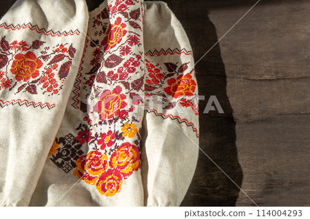 Ukrainian clothes embroidered shirt. Red orange and black threads background. Vyshyvanka is a symbol of Ukraine. Embroidery cross stitching. National Ukrainian stitch. Traditional clothing symbol 114004293