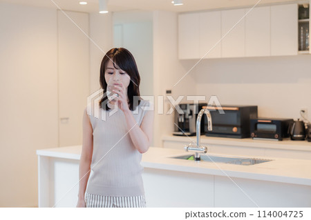Young woman drinking water at home 114004725