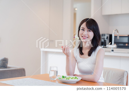 Young woman eating at home 114005570