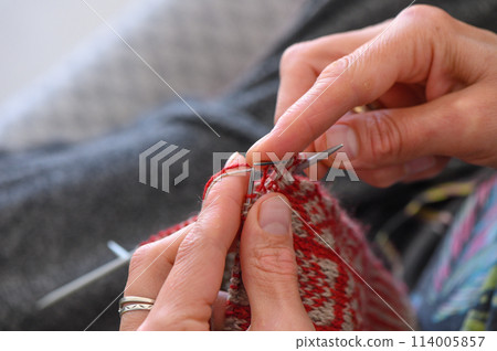 woman sitting on sofa, skillfully knitting warm socks 1 114005857