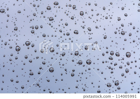 raindrops on glass window of car with cloudy sky in the background 2 114005991