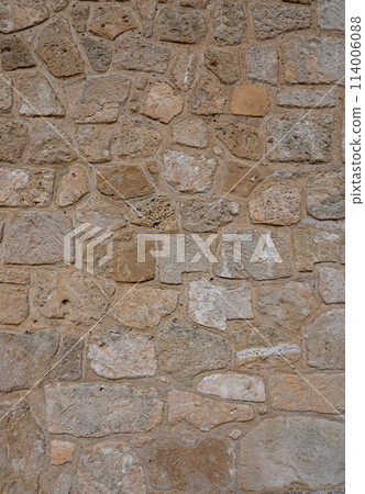 Old coarse panoramic stone wall made of various square natural stones in beige, ocher and brown 114006088
