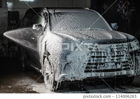 Man applying foam to black car in car wash. Man applying foam to black car in car wash. 114006265