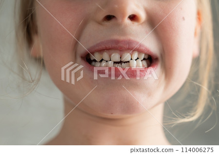 A cute little girl smeared in chocolate eats cookies while lying on the sofa. 114006275