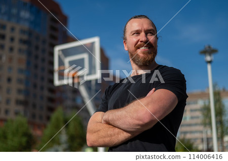 Portrait of a Caucasian bearded man on a basketball court outdoors. Portrait of a Caucasian bearded man on a basketball court outdoors. 114006416
