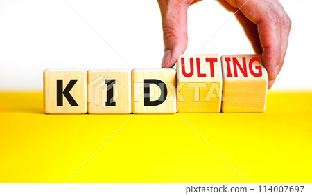 Kid or kidulting symbol. Concept words Kid or Kidulting on wooden cubes. Beautiful yellow table white background. Psychologist hand. Healthy lifestyle and kid or kidulting concept. Copy space. 114007697