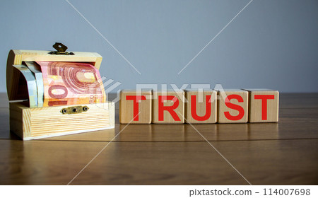 Concept word trust on cubes on a beautiful wooden table, small chest with euro bills. Concept word trust on cubes on a beautiful wooden table, small chest with euro bills. 114007698