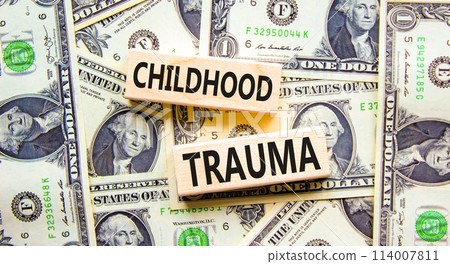 Childhood trauma symbol. Concept words Childhood trauma on beautiful wooden blocks. Dollar bills. Beautiful background from dollar bills. Business psychology childhood trauma concept. Copy space. 114007811