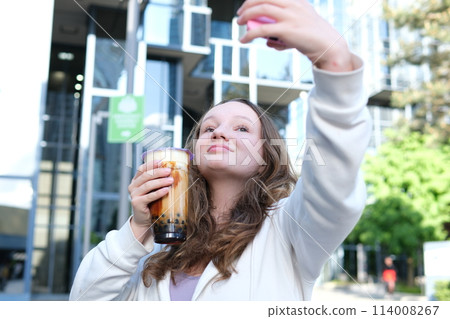 Beautiful girl drinks smoothies from a straw in a cafe. drink bubble tea take selfie Beautiful girl drinks smoothies from a straw in a cafe. drink bubble tea take selfie 114008267