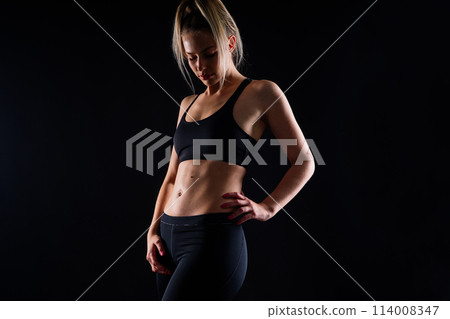 Middle aged woman doing fitness workout, standing in activewear with abs and muscles, smiling happy 114008347