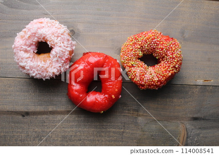 Three donuts red, pink, white, glazed on a gray background with space for text. Donut Day is sugar food. Sugar in Foods Bad Carbohydrates 114008541