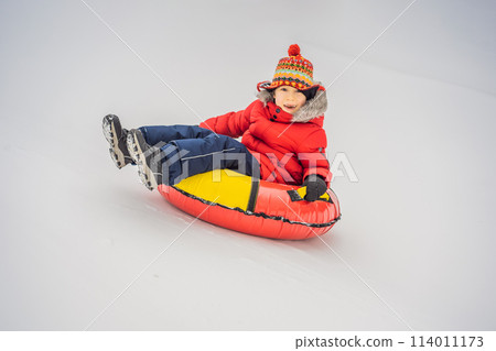 Child having fun on snow tube. Boy is riding a tubing. Winter fun for children 114011173