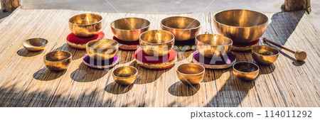 Tibetan singing bowls on a straw mat against a waterfall BANNER, LONG FORMAT 114011292