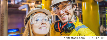 Man and woman in a yellow work uniform, glasses, and helmet in an industrial environment, oil Platform or liquefied gas plant BANNER, LONG FORMAT 114012108