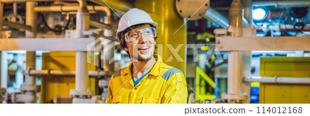 Young man in a yellow work uniform, glasses and helmet in industrial environment,oil Platform or liquefied gas plant BANNER, LONG FORMAT 114012168