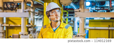 Young man in a yellow work uniform, glasses and helmet in industrial environment,oil Platform or liquefied gas plant BANNER, LONG FORMAT Young man in a yellow work uniform, glasses and helmet in industrial environment,oil Platform or liquefied gas plant BANNER, LONG FORMAT 114012169