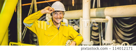 Young man in a yellow work uniform, glasses and helmet in industrial environment,oil Platform or liquefied gas plant BANNER, LONG FORMAT 114012171