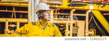 Young man in a yellow work uniform, glasses and helmet in industrial environment,oil Platform or liquefied gas plant BANNER, LONG FORMAT Young man in a yellow work uniform, glasses and helmet in industrial environment,oil Platform or liquefied gas plant BANNER, LONG FORMAT 114012173