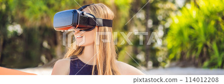 BANNER, LONG FORMAT Summer lifestyle portrait of pretty girl sitting on the orange inflatable sofa and uses virtual reality headset on the beach of tropical island. Relaxing and enjoying life on air BANNER, LONG FORMAT Summer lifestyle portrait of pretty girl sitting on the orange inflatable sofa and uses virtual reality headset on the beach of tropical island. Relaxing and enjoying life on air 114012208