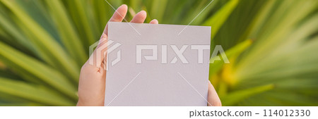 Women's hands in a tropical background holding a signboard paper, mockup BANNER, LONG FORMAT 114012330