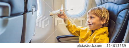 Little boy play with toy plane in the commercial jet airplane flying on vacation BANNER, LONG FORMAT 114013389