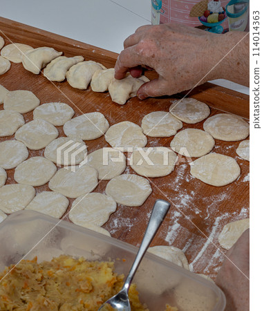 On the wooden counter top Woman hands are making a damp dumpling On the wooden counter top Woman hands are making a damp dumpling 114014363