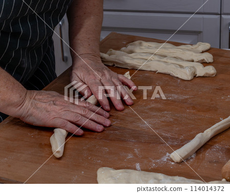 Female hands knead the dough on a wooden table Female hands knead the dough on a wooden table 114014372