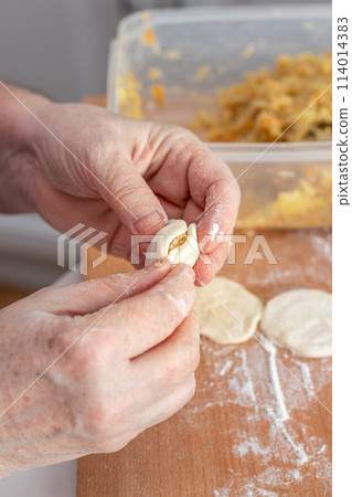 Woman hands are making a damp dumpling. . Woman hands are making a damp dumpling. . 114014383