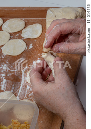 On the wooden counter top are some raw dumplings in flour 114014386