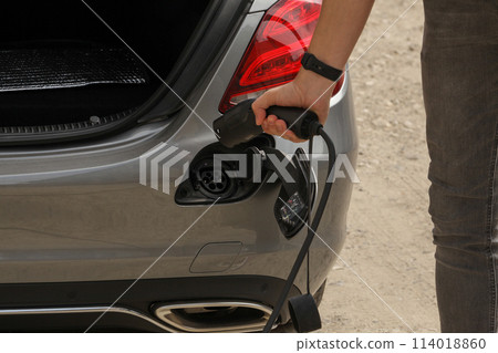 Picture of a person who wants to put into operation the portable electric charger for a gray car. Picture of a person who wants to put into operation the portable electric charger for a gray car. 114018860
