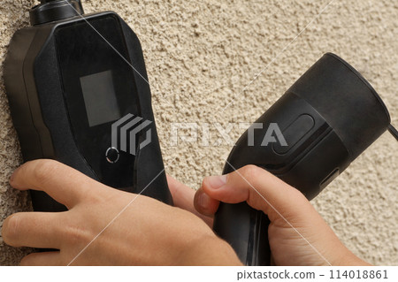 New 2023 new model black portable charger for cars sitting on a gray wall. New 2023 new model black portable charger for cars sitting on a gray wall. 114018861
