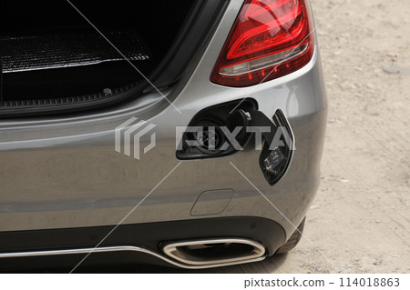 The place intended for the portable charger for electric cars. Picture of the gray car in the parking lot. 114018863