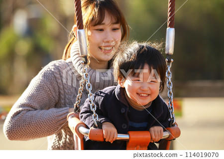 Parents and children playing on a swing 114019070