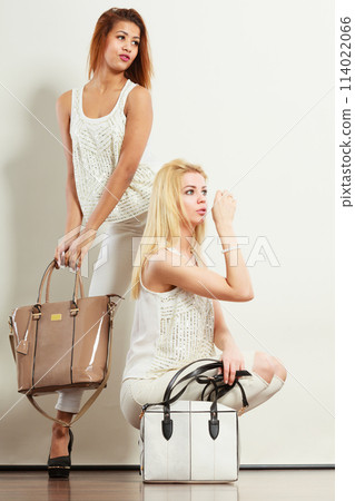 Two women in white clothes with bags handbags. 114022066