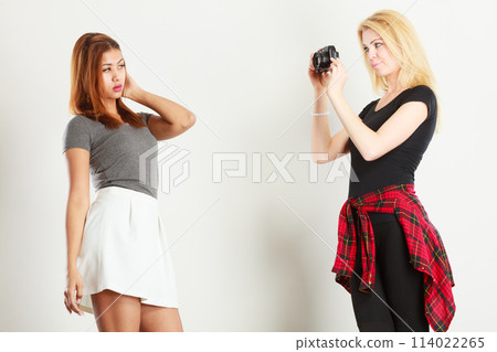 Blonde girl photographing mulatto woman 114022265