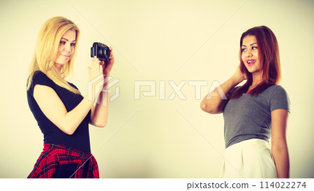 Blonde girl photographing mulatto woman Blonde girl photographing mulatto woman 114022274