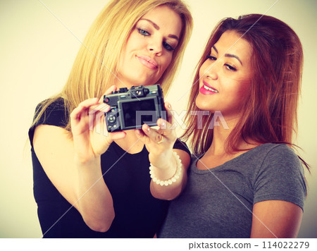 Two models girls taking self picture with camera 114022279