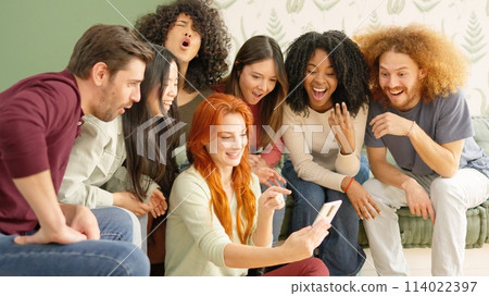 Friends looking at a mobile and laughing at one video 114022397