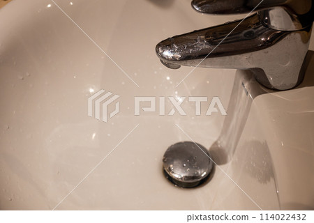 Close up of bathroom sink with running water from faucet Close up of bathroom sink with running water from faucet 114022432