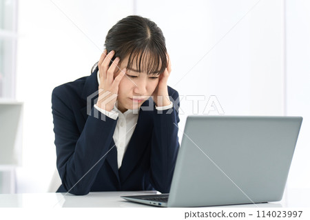 Business woman holding her head in front of a computer 114023997