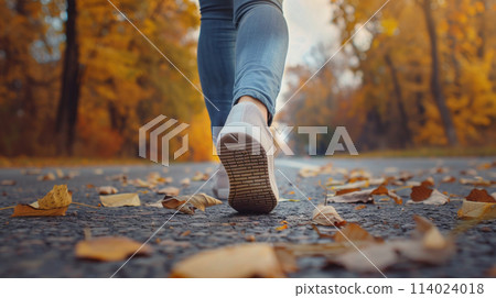 Feet of a woman walking on the autumn road 114024018