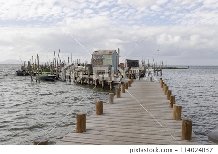 A pier with a wooden walkway leading to a small house A pier with a wooden walkway leading to a small house 114024037