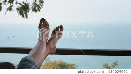 A person laying down with their feet raised up in the air, as if they are relaxing and stretching. 114024651