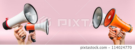 Hands holding megaphones against a pink background. Megaphones in hands for advertising and information campaigns. Hands holding megaphones against a pink background. Megaphones in hands for advertising and information campaigns. 114024770