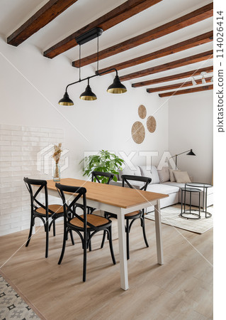 Dining table with chairs under metal luster in apartment Dining table with chairs under metal luster in apartment 114026414