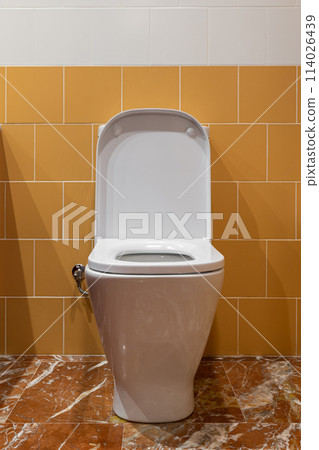 White toilet with yellow tiles, marble flooring, rectangle toilet seat and opened lid White toilet with yellow tiles, marble flooring, rectangle toilet seat and opened lid 114026439
